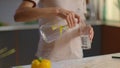 Woman pouring water into glass from jug at home. Girl drinking water on kitchen Royalty Free Stock Photo