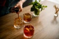 Close-up woman pours drink from jigger into glass