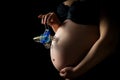 Close-up of woman pregnant belly with a toy pram. Girl tenderly holding her tummy with child. Concept of pregnancy, mother`s love