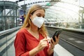 Close-up of woman with protective face mask using smartphone in Berlin train station on sunset, Germany Royalty Free Stock Photo