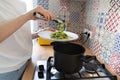 Close up of woman puts the fettuccine pesto paste from saucepan on a plate. Homemade italian cuisine