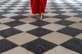 Close up of a woman in red dress and elegant sandals walking on a checkered marble black and white floor Royalty Free Stock Photo