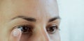 Close-up of a woman removing soft contact lenses from her eye against a white background