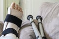 Woman`s foot which is injured and is wearing a brace and crutches