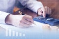 Close up of woman s hand with a calculator. She is holding a pen ready to take notes in her notebook. Clipboard. Toned image doubl Royalty Free Stock Photo