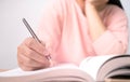 Close up of Woman`s hand drawing a line and writing short summary while reading a book at library Royalty Free Stock Photo