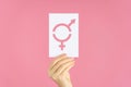 Close-up of a woman`s hand holding a card with a symbol of gender equality on a pink background Royalty Free Stock Photo