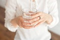 Close-up of a woman`s hand holding a cold glass of water and ice over a white background. Royalty Free Stock Photo