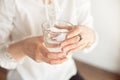 Close-up of a woman`s hand holding a cold glass of water and ice over a white background. Royalty Free Stock Photo