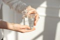 Close-up of a woman`s hand holding a cold glass of water and ice over a white background. Royalty Free Stock Photo