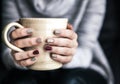 Close-up of a woman`s hand holding a cup of hot coffee. fashion, leisure Royalty Free Stock Photo