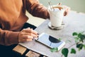 Close up of woman hands with beautiful manicure who uses cell phone and drinks cup of tea. Royalty Free Stock Photo