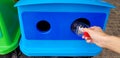 Close up woman`s hand holding and dumping plastic bottle of water into blue recycle bin, trashcan or trash Royalty Free Stock Photo