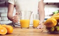 Close up of woman`s hand holding glass carafe or jug. Drinking orange juice at home in the kitchen. Healthy eating, morning Royalty Free Stock Photo