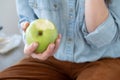 Close up of woman`s hand holding a healthy and appetizing green apple