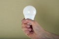 Close up of woman`s hand holding light bulb. Green background Royalty Free Stock Photo