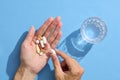 Close up of a woman's hand holding multiple pills with a glass of water. Royalty Free Stock Photo