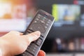 Close-up of woman`s hand holding remote control in front of TV Royalty Free Stock Photo