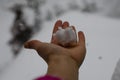 Close-up of a woman`s hand holding a snow cake against the background of a strong snowstorm and blizzard