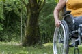 Close-up of a woman`s hand holding the wheel of a wheelchair, from the front, in the countryside Royalty Free Stock Photo