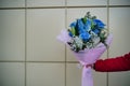 Close up of woman`s hand holds colorful bouquet of flowers. Unrecognizable female holding flower composition of blue roses and Royalty Free Stock Photo