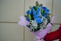 Close up of woman`s hand holds colorful bouquet of flowers. Unrecognizable female holding flower composition of blue roses and Royalty Free Stock Photo