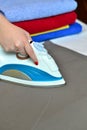 Close-up of woman's hand ironing clothes on the table against th