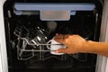 Close-up of a woman`s hand loading dishes, emptying or unloading them from an open automatic built-in dishwasher with dishes insi Royalty Free Stock Photo