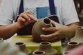 Close-up of a woman`s hand making patterns on a clay vase in a pottery workshop. Process of making a ceramic vase. handicraft and