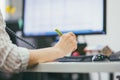 Close-up of a woman`s hand with a pen on the background of the monitor. She`s on the phone. Office workdays. Selective