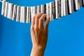 Close-up of a woman`s hand playing the imaginary piano made from clothes pins on blue paper background Royalty Free Stock Photo