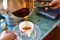 Close up of a woman`s hand pouring herself a mug of hot black herbal tea from a steel pot Royalty Free Stock Photo
