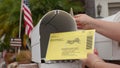 Close up of a woman`s hand putting mail ballot into mailbox