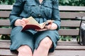 Close-up of a woman`s hand reading a book while sitting on a park bench Royalty Free Stock Photo