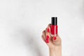 Close-up of woman`s hand with red nail design holding nail polish bottle. Royalty Free Stock Photo