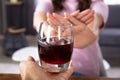 Woman Refusing Glass Of Drink Offered By Person