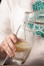 Close-up of woman`s hand serving tonic in a glass with lemon,