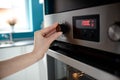 Close up of woman's hand setting temperature control on oven