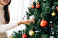Close up woman's hand touching and decorating a red bauble on the Christmas tree in the living room at home. Royalty Free Stock Photo