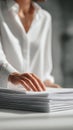 Close-up of a woman's hand touching a large stack of documents on a desk, dressed in white Royalty Free Stock Photo