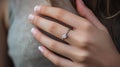 Close-up of a woman\'s hand wearing an engagement ring