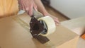 Close up on a woman`s hands closing a cardboard box with adhesive tape