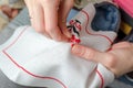 Close-up of a woman`s hands cross-stitching on a white canvas. A woman embroiders the national symbols of Ukraine