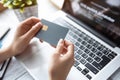 Close up of a woman& x27;s hands holding a gray credit card in front of a laptop computer Royalty Free Stock Photo