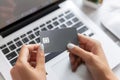 Close up of a woman& x27;s hands holding a gray credit card in front of a laptop computer Royalty Free Stock Photo