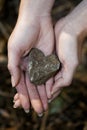 Close up on woman`s hands holding small Heart-shaped stone, vertical photo Royalty Free Stock Photo