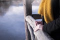 Close up of a woman`s hands leaning on wooden fence enjoying view on cold lake - traveling, trip to nature