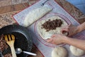 Close up of a woman`s hands making dough for homemade bread on a silicone baking sheet. frying pan with grinned meat on the side