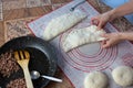 Close up of a woman`s hands making dough for homemade bread on a silicone baking sheet. frying pan with grinned meat on the side