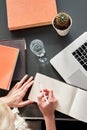 Close up of woman`s hands making notes on white spread book. cactus and glass of water. Young woman or student working and writing Royalty Free Stock Photo